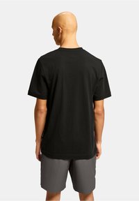 Sort bomulds T-shirt med korte ærmer og klassisk rund halsudskæring, båret med grå shorts. Minimalistisk design, ingen synlige mønstre eller accenter.