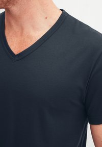 Donkerblauwe V-hals t-shirt gemaakt van soepel katoen. Bevat een schone halslijn en korte mouwen, en toont een getailleerde silhouet.