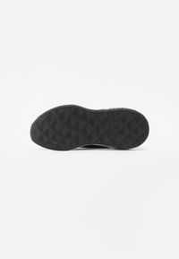 Sole di scarpa in gomma nera con un motivo testurizzato caratterizzato da scanalature e forme a diamante per una maggiore aderenza. Design della suola piatto e arrotondato.