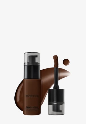Flacon de fond de teint liquide marron avec pompe noire à côté d'une baguette applicatrice ouverte et des échantillons sur fond blanc.