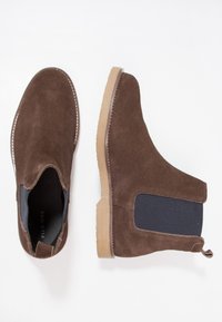 Braune Wildleder Chelsea-Stiefel mit elastischen Seitenpaneelen, weichem Textur und Gummisohlen. Mit einer Schlaufe an der Ferse für ein einfaches Anziehen.