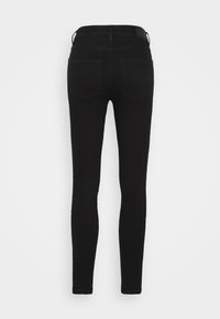 Jeans ajustados negros hechos de mezclilla, con una cintura de media altura, dos bolsillos traseros y un diseño simple sin herrajes visibles.
