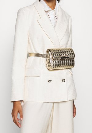 Witte getextureerde double-breasted blazer met parelknopen, bijpassende broek en goudkleurige metalen gewatteerde riemtas gedragen in de taille.