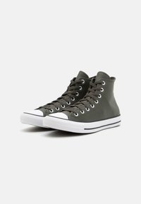 Gröna högskor med en slät läderöverdel, vit tådel, svarta ögla och vit mellansula med svarta ränder.