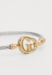 Silver cable bracelet featuring a gold-tone GG clasp with crystal accents, combining metal and cable textures.