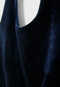 Námornícka modrá zamatová tkanina s hladkým povrchom a jemným leskom; má okrúhly výstrih a jemné splývanie.