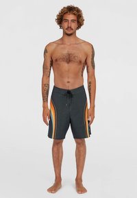 Bañador corto negro con rayas naranja-amarillas en los laterales, hecho de material ligero, con cintura ajustable mediante cordón y detalle de botones en el costado.