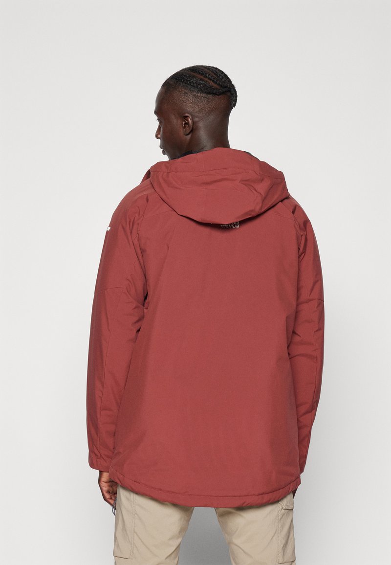 Giacca isolante bordeaux con cappuccio, caratterizzata da una texture morbida e un orlo posteriore più lungo, progettata con un branding minimalista sulla parte superiore della schiena.