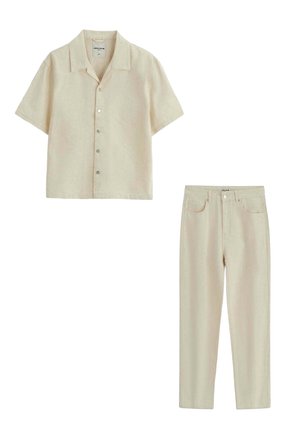 Chemise beige à manches courtes boutonnée avec col et pantalon droit taille haute assorti sur fond blanc.