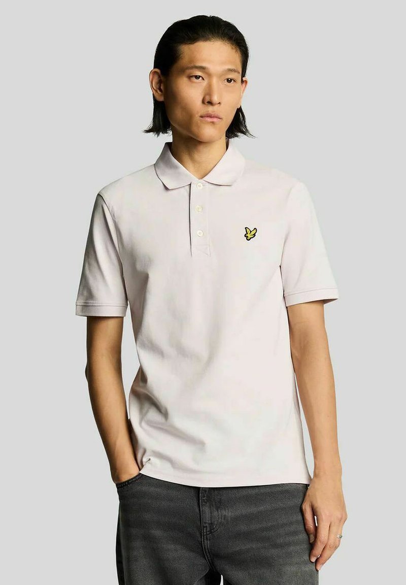 Lichtroze poloshirt van katoen, met een omgeslagen kraag, drieknopenbies en een klein geel vlindertje op de borst.