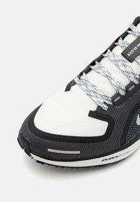 Mens running shoes with a mix of white mesh and dark gray textured material, featuring reflective accents and gray laces. Rubber sole visible.