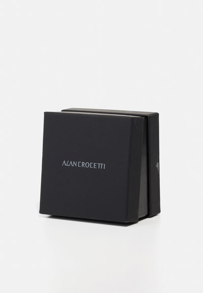 Black cardboard box with a matte finish, featuring "ALAN CROSETTI" in silver lettering on the front, folded design with sharp edges.