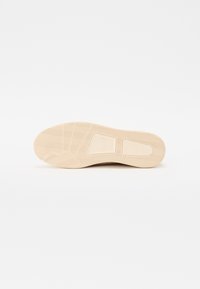 Suola della scarpa in gomma testurizzata di un beige chiaro, con un motivo a zigzag e un design a blocco rettangolare al centro.