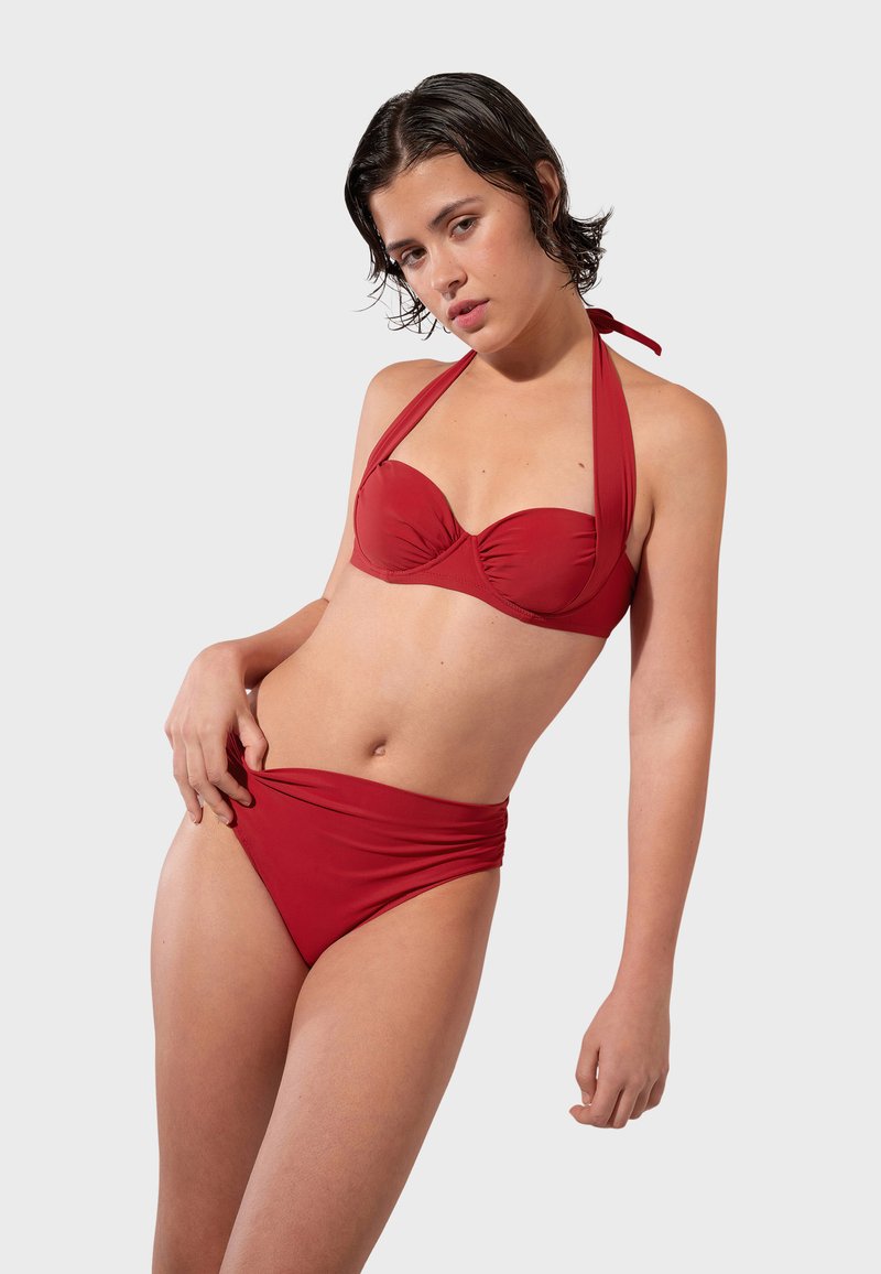 Červený bikiny set so zaväzovaním za krkom, mäkkými košíčkami a vysokými plavkami. Hladký materiál v jednotnej farbe s minimálnymi detailmi dizajnu.