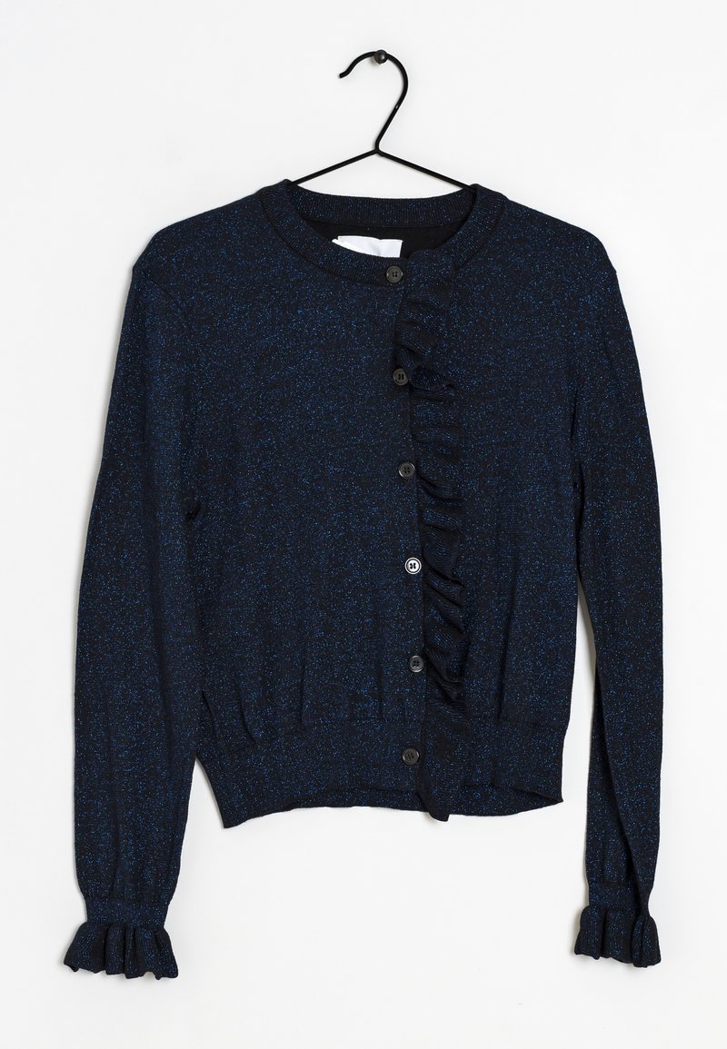 Cardigan bleu marine à manches longues avec boutons sur le devant, bordure à volants sur un côté et aux poignets, suspendu à un cintre noir.