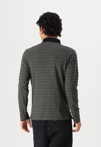 Langarm-Polohemd in Dunkelgrau mit hellen Streifen, ausgestattet mit einem schwarzen Kragen und weichem Stoff. Die Rückansicht zeigt ein tailliertes Design und Manschettendetails.