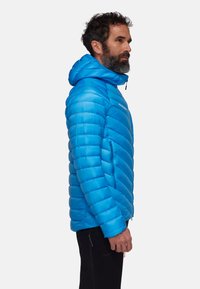 Veste isolante bleue avec motif matelassé vertical, dotée d'une capuche et de poches zippées. Texture lisse avec des finitions en métal durables.