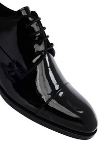 Chaussure habillée en cuir verni noir avec un bout arrondi, des lacets fins et une finition lisse et brillante ; présente un design classique à bout coqué.