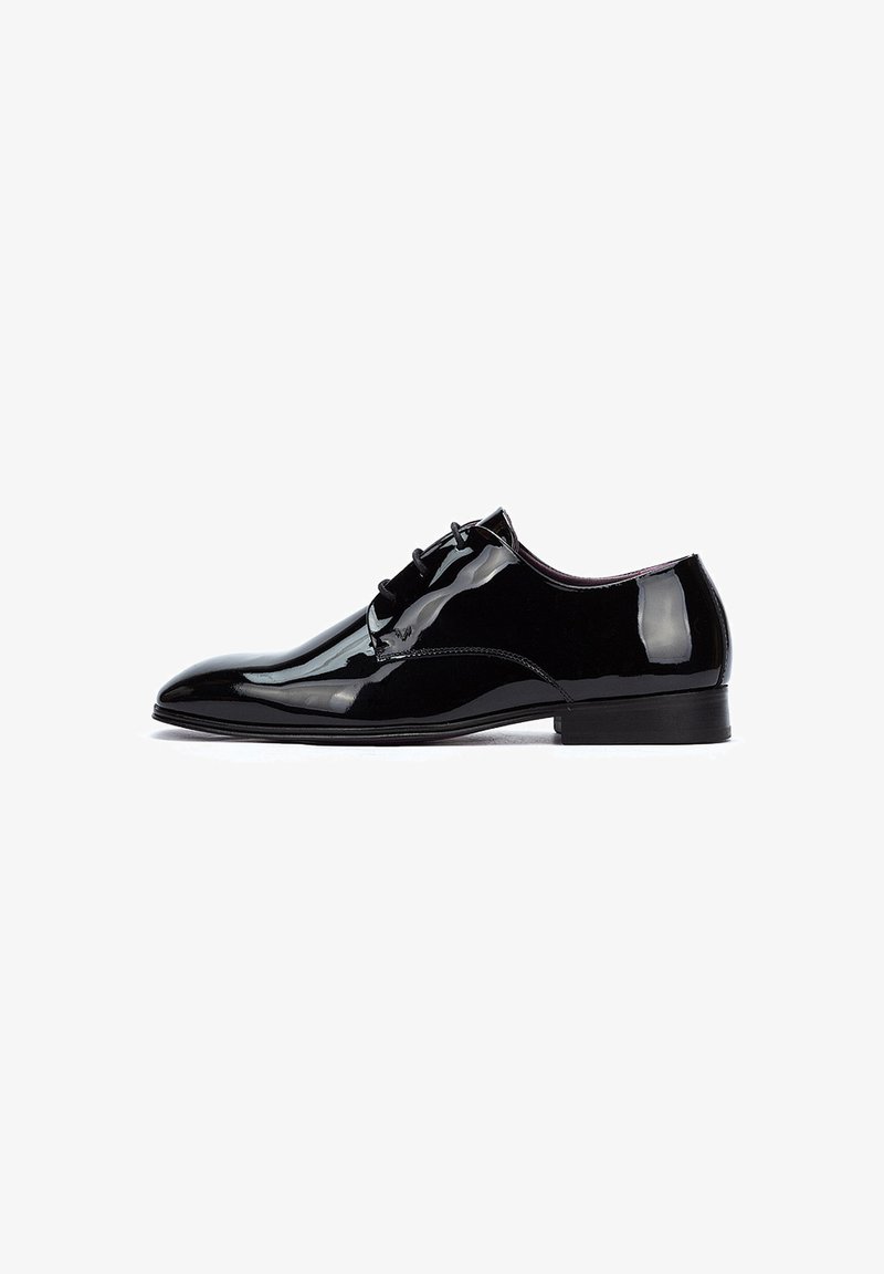 Zapato oxford de charol negro con un diseño elegante, punta redonda y cierre con cordones. Superficie lisa y brillante con tacón bajo.