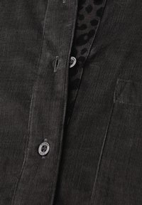 Zwarte corduroy shirt met knoopsluiting aan de voorkant, textuurstof en contrasterende luipaardprint voering onder de kraag.