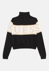 Črno in krema pletena jopica z visokim ovratnikom. Ima vodoravni GUESS logotip v zlati barvi. Ribo obrobljeni manšeti in spodnji rob. Skrajšana zasnova.