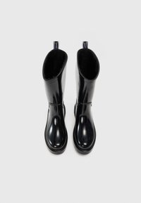 Bottes en caoutchouc noires montantes avec une finition brillante, bout arrondi et doublure texturée à l'intérieur. Comprend des languettes pour un enfilage facile.