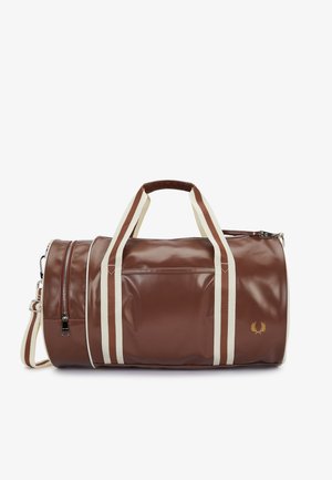 Sac de voyage en cuir marron avec des anses rayées crème et marron, une poche zippée latérale et un petit logo laurier doré sur le devant.