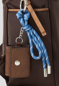 Borsa di tessuto marrone con un accento in pelle, dotata di un portachiavi a corda blu e bianca e di un portaccessori coordinato in pelle marrone.