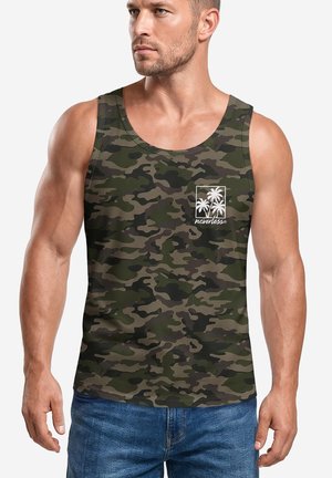 Muskelbepackter Mann trägt ein grünes und braunes Camouflage-Tanktop mit kleinem weißem Palmenlogo und Text auf der Brust, kombiniert mit blauen Jeans.