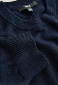 Tumesinine kudum sweatshirt soontega ja tekstuursete küünarnukipatchidega. Sildi peal on "NEXT." Pehme kangas sujuva viimistlusega.