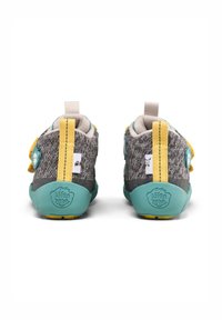 Scarpe di stoffa grigie con suola teal, accenti gialli e chiusura a bottone. La parte posteriore presenta un anello per facilitare l'indossamento.