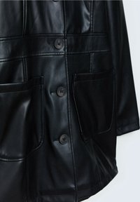 Chaqueta de cuero negro con un diseño estructurado, textura brillante, cuatro bolsillos delanteros y cierres distintivos con botones.
