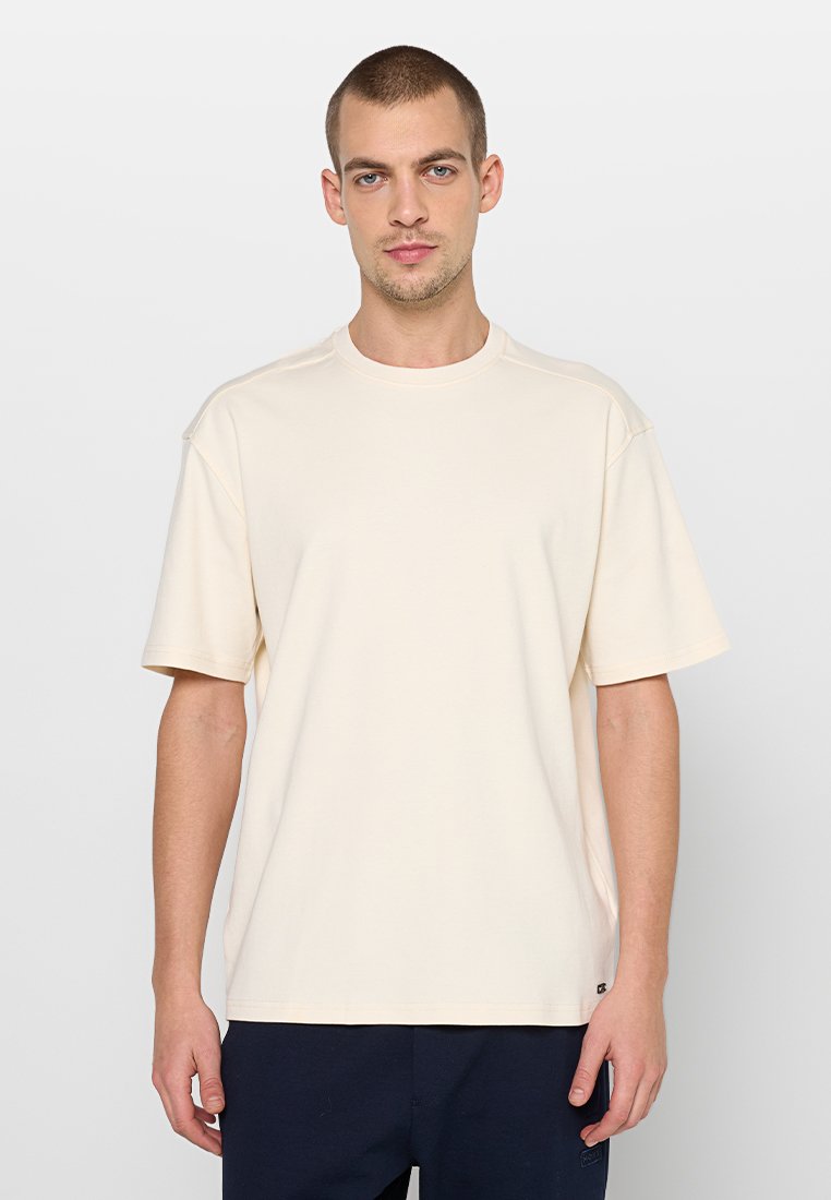 T-shirt met korte mouwen en ronde hals in lichtbeige katoen. Voorzien van zijnaden en een ontspannen pasvorm. Subtiel merkembleem aan de onderzoom.