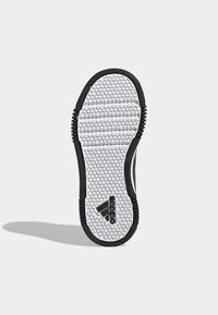 Sko sula med en texturerad mönster med hexagonala grepp i svart och vitt, märkt med en svart Adidas-logotyp.