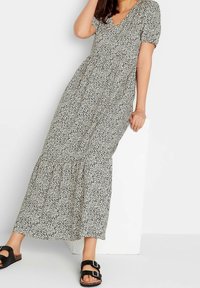Maxi sukienka w kremowym kolorze w czarne plamki, z krótkimi bufiastymi rękawami, dekoltem w serek i marszczoną talią. W zestawie z czarnymi sandałami.
