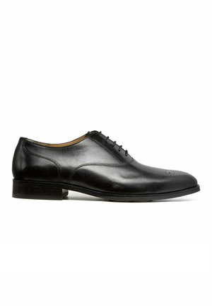 Chaussure Oxford formelle pour homme en cuir noir avec laçage fermé et décoration perforée subtile sur l’avant, vue de côté.