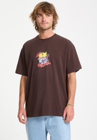 Brun bomulds t-shirt med et farverigt grafisk design på brystet. Klassisk pasform med korte ærmer og rund hals.