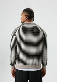 Gestreepte trui met contrasterende zwarte en roomkleurige lijnen, geribbelde manchetten en zoom. Zachte textuur, casual silhouet.