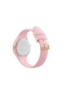Orologio in silicone rosa con fibbia in metallo dorato, cassa rotonda in argento sul retro e aperture sul cinturino per la regolazione.