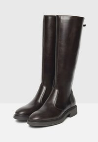 Bottes en cuir marron jusqu'au genou avec une finition lisse, des panneaux latéraux élastiques et un petit talon carré. Détails de couture le long des coutures.