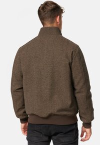 Brauner Fischgrätjacke mit hohem Kragen, gerippten Bündchen und Saum. Verfügt über einen strukturierten Stoff und eine lockere Passform. Rückansicht gezeigt.