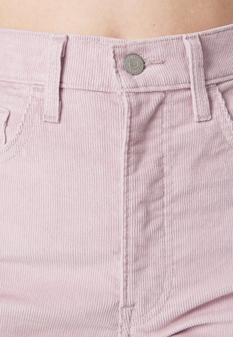 Shorts en velours rose clair avec une texture côtelée verticale, dotés d'une fermeture à bouton à l'avant et d'un design standard à cinq poches.
