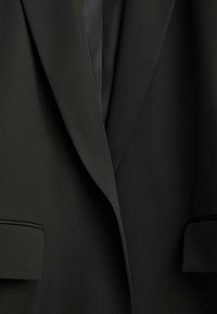 Black blazer featuring a notched lapel, smooth texture, and two front pockets. The fabric appears lightweight and slightly glossy.