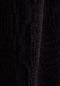 Svart stickad tyg med en fin textur, som har en slät yta och en subtil lyster. Bilden visar tygets veck och ljusreflektioner.