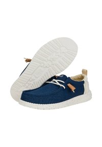 Scarpe in tela blu navy con suole in gomma bianche a pois, chiusura con lacci e accenti beige. L'interno morbido aumenta il comfort.