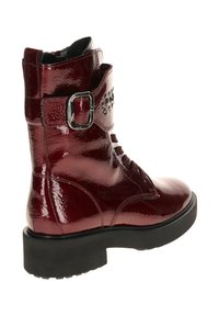 Red patent leather ankle boot with lace and side buckle detail, featuring a textured finish and a thick black sole.