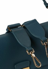 Borsa a mano in pelle turchese con accessori color oro, caratterizzata da finitura testurizzata, tracolla regolabile e attacchi a clip. Design liscio e strutturato.