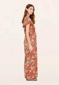 Lange, bloemen maxi-jurk in roestkleur met gerokte korte mouwen, voorzien van een textuurpatroon en kleurrijke bloemenaccenten.