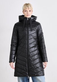 Svart pufferjakke med hette, med glidelås foran, chevron-quilting og snor-detaljer. Laget av blankt syntetisk materiale.