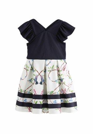 Robe avec un haut bleu marine à manches volantées, décolleté en V, et une jupe blanche à motif floral avec des accents bleus et verts, ainsi qu'un ourlet rayé bleu marine.